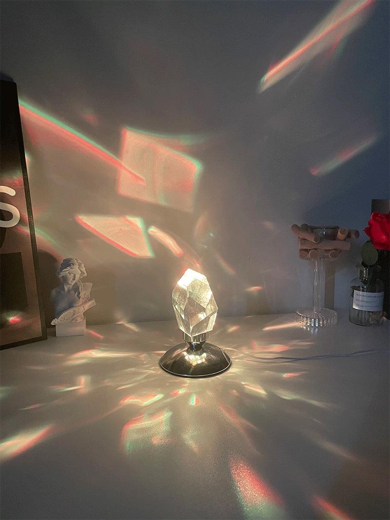 Crystal prism lamp casting colorful light reflections on white desk with decorative items