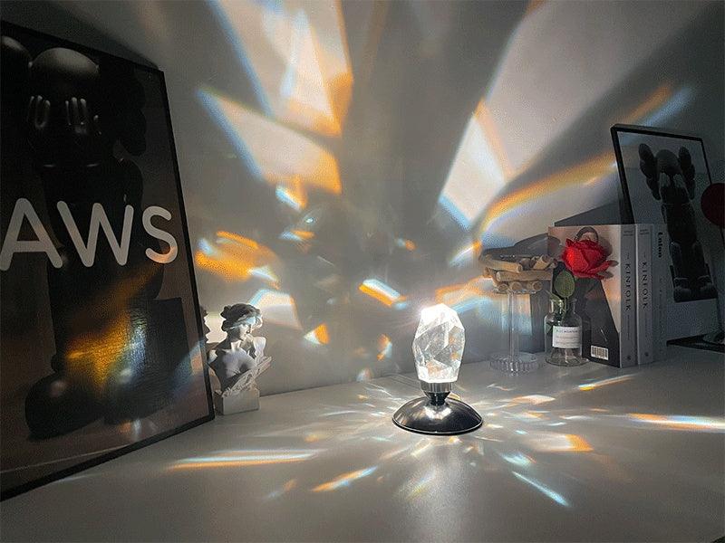 Crystal prism lamp casting colorful light patterns on a desk with framed art and decorative items