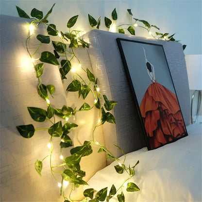 String lights with green vine leaves decorating a beige headboard next to a framed art print of a woman in a red dress