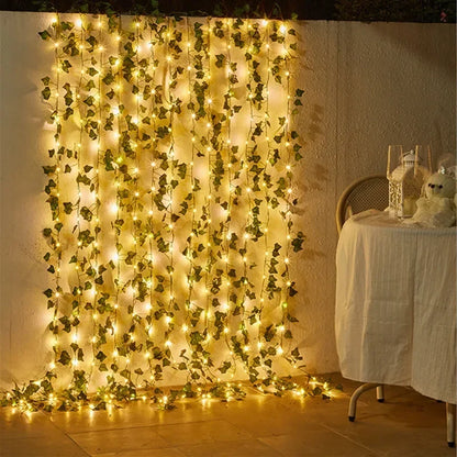 String lights with green ivy leaves draped on wall next to table with white cloth and wine glasses