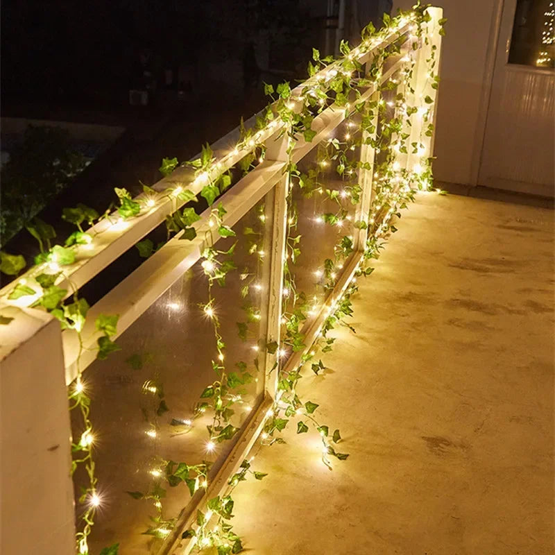 Balcony railing decorated with glowing warm white string lights and green ivy vines at night