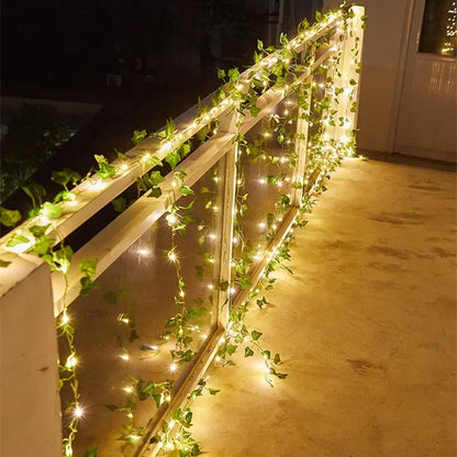 Balcony railing decorated with glowing warm white string lights and green ivy vines at night