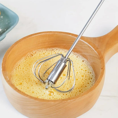 Whisk mixing frothy beaten eggs in wooden bowl on white surface