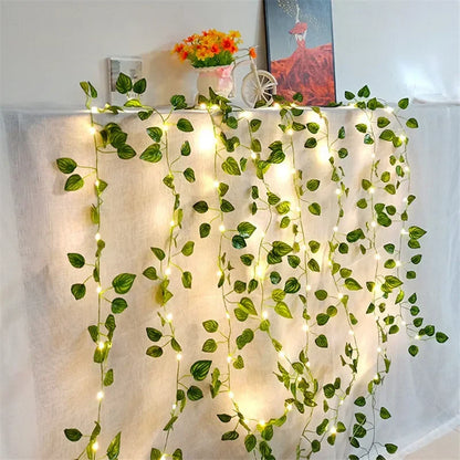 Decorative hanging artificial green ivy vines with string LED lights on white fabric backdrop