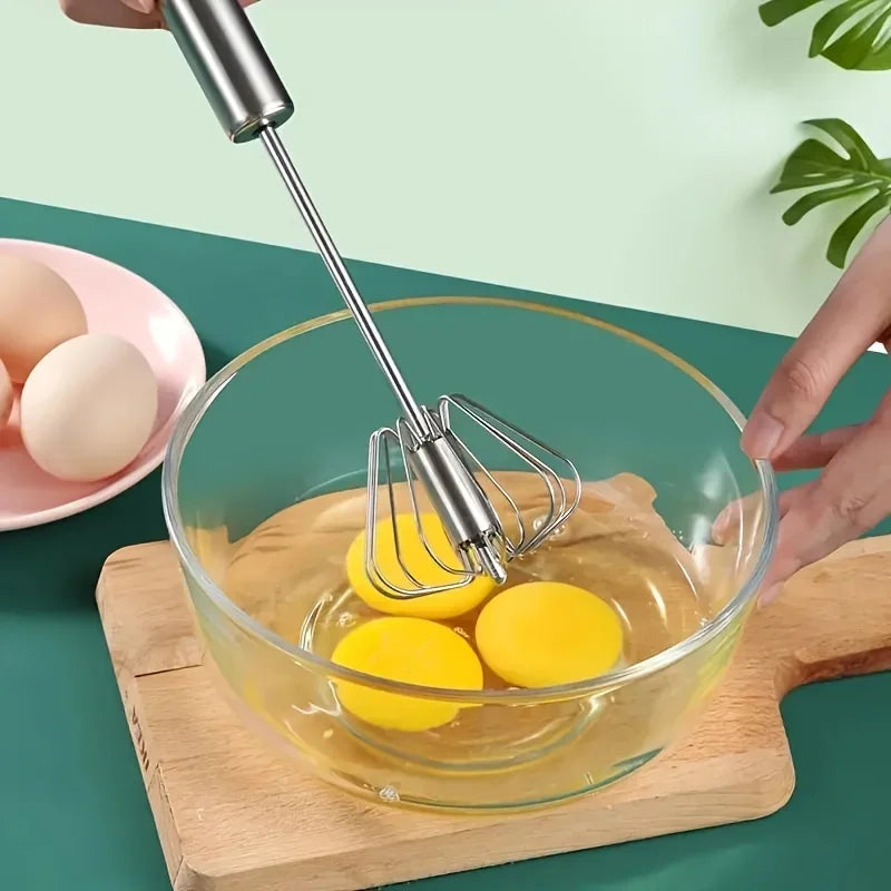 Hand whisking three egg yolks in a glass bowl on a wooden cutting board with eggs on a pink plate