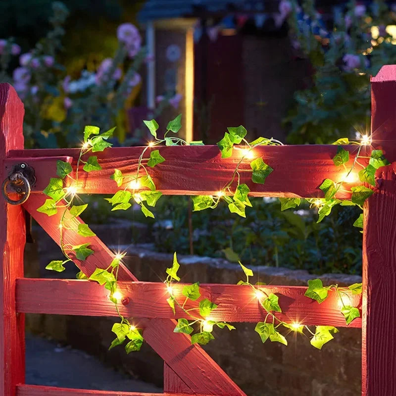 Red wooden garden gate decorated with glowing green ivy fairy lights at dusk