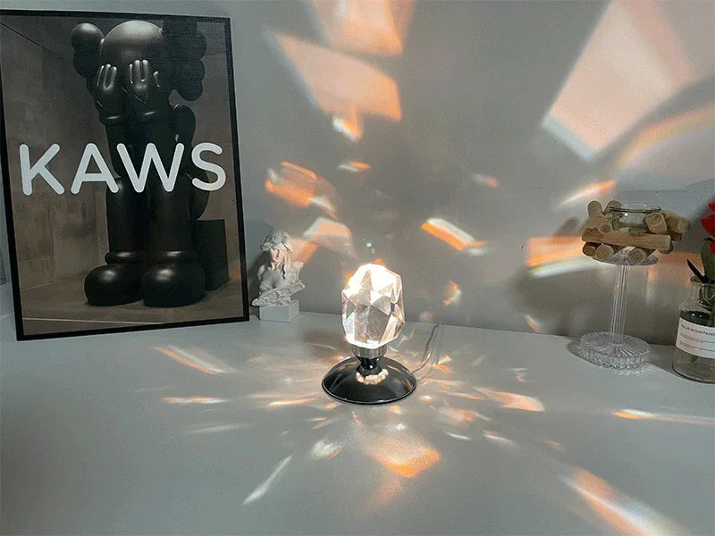 Crystal prism lamp on a white desk casting colorful light reflections with art poster and small statues